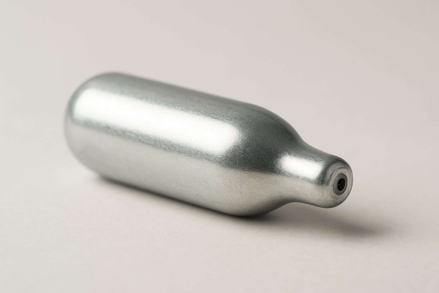 Close-up of a silver cream charger on a neutral background